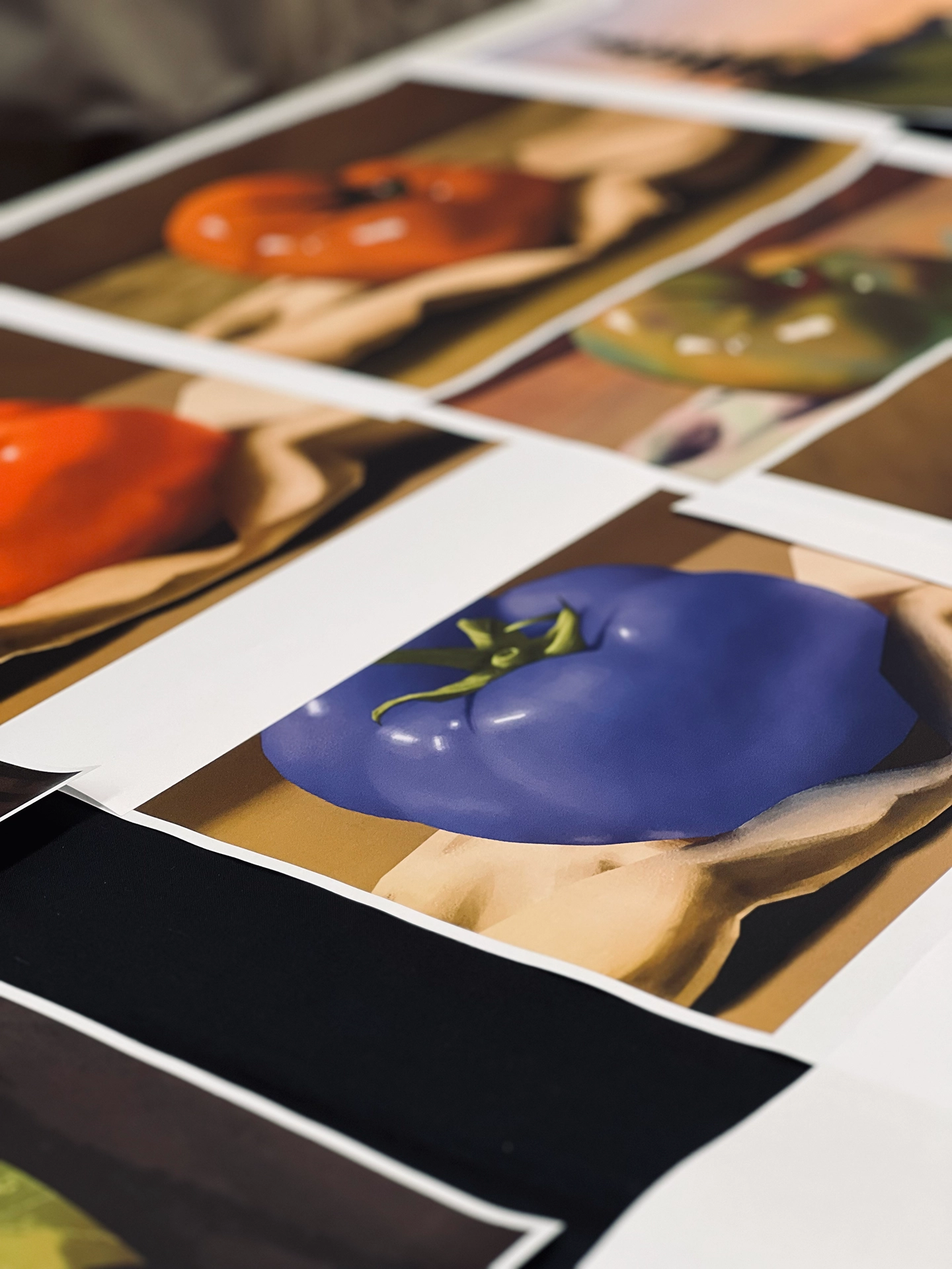Mehrere fotorealistisch gemalte Gemüse-Motive auf Papiertüten liegend, im Fokus eine lila Paprika, im Hintergrund weitere Motive wie Tomaten und eine grüne Frucht